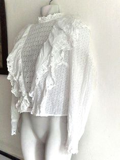 Pretty high neck broderie anglaise cotton blouse in white with yolk frills, long sleeves, button cuffs and key hole cut out back. No labels approx Size UK8 US4 Measurements: Pit to pit 17" (34" bust) Length 20" Sleeve 17" shoulder to shoulder back 14" Good pre-loved condition  *model size UK10/12 but too small All orders are shipped using biodegradable and recycled packaging where possible Broderie Anglaise Long Sleeve Blouse For Fall, Long Sleeve Broderie Anglaise Blouse For Fall, Fall Long Sleeve Broderie Anglaise Blouse, Cottagecore Long Sleeve Blouse With Lace Collar, Victorian Cotton Tops For Spring, Spring Victorian Cotton Tops, White Long Sleeve Top With Boho Collar, White Swiss Dot Top For Fall, Cottagecore Blouse With Ruffled Collar