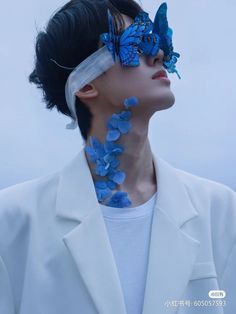 a woman with blue flowers on her neck and butterfly in her hair, wearing a white jacket