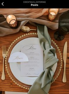 a place setting with napkins, silverware and candles on a wooden table top