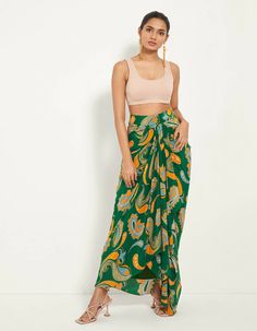 Swing into summers in this paisley printed draped skirt, customised in a flattering asymmetric silhouette to highlight the slit. Pair it with a bustier and matching overlay to spend the evening by the beach. Up the ante with an oversized blazer and gladiator heels for a formal dinner. Summer Draped Flowy Skirt, Fitted Paisley Print Skirt For Summer, Asymmetrical Green Maxi Skirt For Beach, Summer Draped Wrap Skirt, Summer Flowy Draped Wrap Skirt, Flowy Draped Summer Wrap Skirt, Fitted Green Wrap Skirt For Vacation, Flowy Draped Wrap Skirt For Summer, Fitted Green Sarong