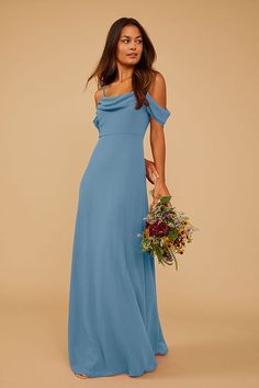 a woman in a blue dress is holding a bouquet and looking off to the side