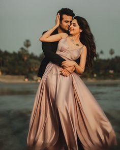 a man and woman hugging each other in front of the ocean