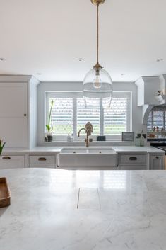 a kitchen with marble counter tops and an island in front of a window that has blind shades on it