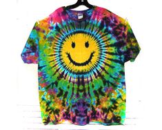 a tie dye smiley face t - shirt hanging on a wall