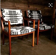 two chairs sitting next to each other in front of a wooden wall with black and white designs on them