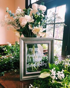 a vase filled with white flowers sitting on top of a table next to a window