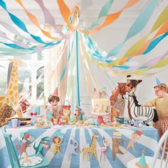 children are gathered around a birthday party with giraffes and zebras on the table