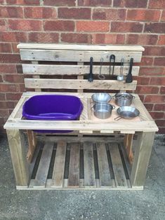 an outdoor stove made out of pallet wood with two bowls and pans on it