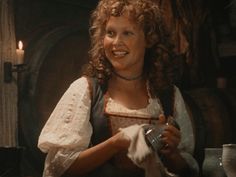 a woman with curly hair is smiling and holding a wine glass in her right hand