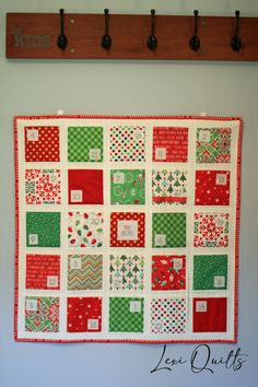 a christmas quilt hanging on the wall with pegs and hooks in front of it