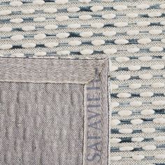 an area rug with white and blue dots on the top, in front of a gray background