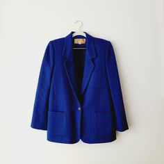 Cobalt blue and black longline wool blazer. The weave is a subtle herringbone pattern that looks like solid blue from far away, but gives dimension up close. 100% wool and fully lined.  Built-in shoulder pads give structure to this classic yet bold blazer. Has two front pockets, one chest pocket, and has a single front button closure and buttons at the sleeve cuffs.  Vintage size 8 - fits like large.  15 inches shoulder seam to shoulder seam,  18.5 inches across the chest,  27.5 inches top of sh Blue Single-breasted Tweed Jacket For Work, Blue Notch Lapel Tweed Jacket For Work, Blue Tweed Notch Lapel Jacket For Work, Blue Tweed Jacket With Notch Lapel For Work, Blue Tweed Jacket With Welt Pockets For Office, Blue Tweed Office Jacket With Pockets, Blue Office Tweed Jacket With Pockets, Blue Notch Lapel Tweed Jacket For Fall, Blue Single Button Blazer For Fall