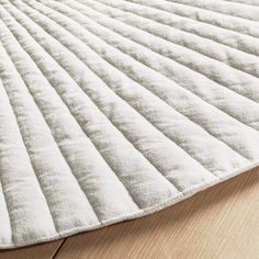 a white rug on top of a wooden floor next to a wood flooring board