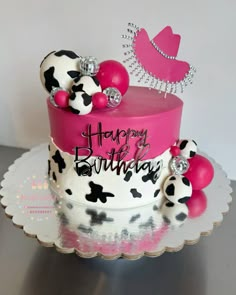 a birthday cake decorated with black and white polka dots, pink frosting, and a tiara