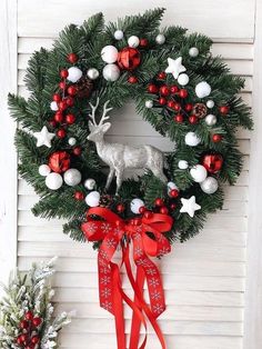 a christmas wreath hanging on the side of a door with red and white ornaments around it