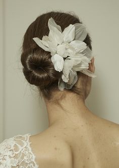 a woman with her back to the camera, wearing a flower in her hair and looking off into the distance