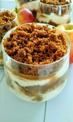 three desserts in glass dishes with apples and cinnamon crumbs on the side