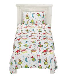 a white bed with christmas themed sheets and pillow cases on it's headboard