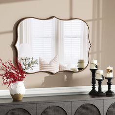 a mirror sitting on top of a dresser next to a vase with flowers in it