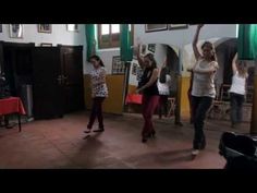 three women are dancing in a room with pictures on the wall