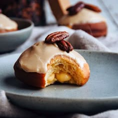 a plate that has some doughnuts on it with icing and pecans