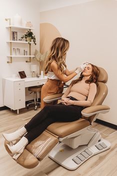 a woman sitting in a chair getting her hair brushed by another woman who is cutting her hair