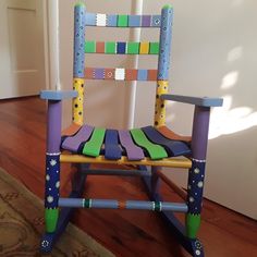 a child's wooden rocking chair made out of strips of colored paper on the floor