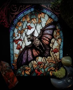 a stained glass window with a bat on it's back and leaves around it