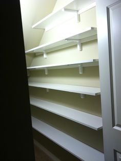 an empty closet with white shelving in it