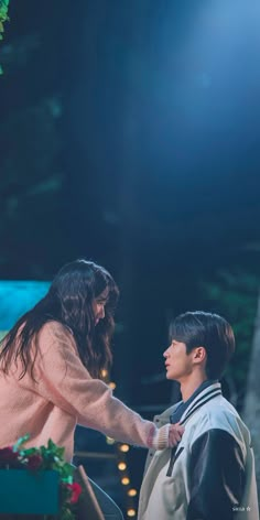 a man and woman standing next to each other in front of a stage with lights