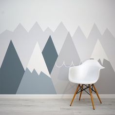 a white chair sitting in front of a wall with mountains painted on it's sides