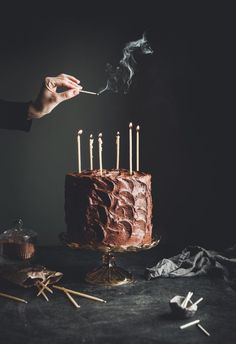 a person lighting candles on a chocolate cake