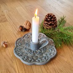 a lit candle sitting on top of a wooden table next to pine cones and acorns