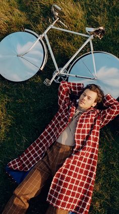 a man laying in the grass next to a bike with mirrors on it's back