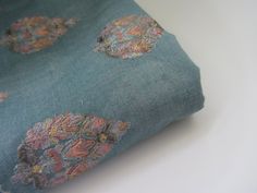 a close up of a blue fabric with flowers and leaves on the bottom half of it