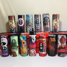 many different colored cans are lined up in a row on a white tableclothed surface