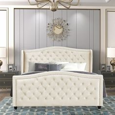 a white bed sitting on top of a blue rug in a bedroom next to dressers