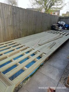 a wooden bed frame being built in the back yard with blue glass inserts on it