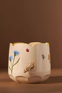 a ceramic bowl with flowers and bugs painted on it