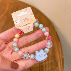 a hand holding a hello kitty bracelet on it's fingers with an animal charm