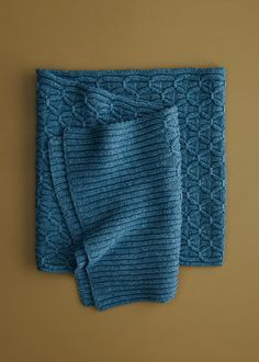 two blue knitted napkins sitting on top of a brown table next to each other