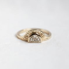 a gold ring with a diamond in the center on a white surface, close up