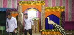 two men standing in front of a decorated stage with flowers and peacocks on it