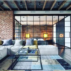 a modern living room with brick walls and glass doors on the wall, along with white couches