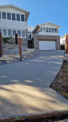 there is a skateboarder riding down the street in front of a house with stone walls