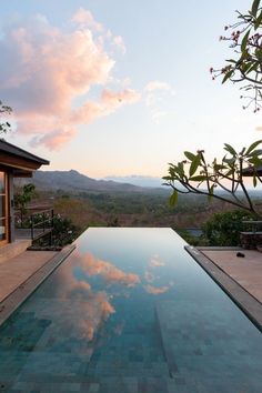 an empty swimming pool with the sky reflecting off it's surface and mountains in the background