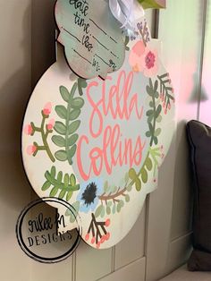 a sign hanging on the side of a door that says sell collins with flowers and leaves