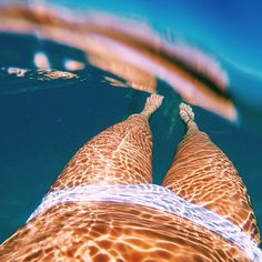 the bottom view of a person's legs as they swim in clear blue water