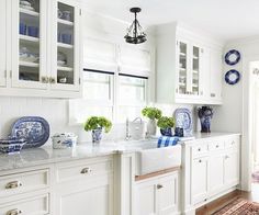 a white kitchen with blue and white dishes on the counter