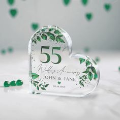 an anniversary card holder with green leaves on it and the number 55 written in white